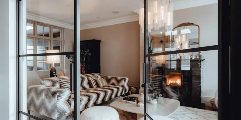 Slim black steel door frames and glass looking through to a warm living room